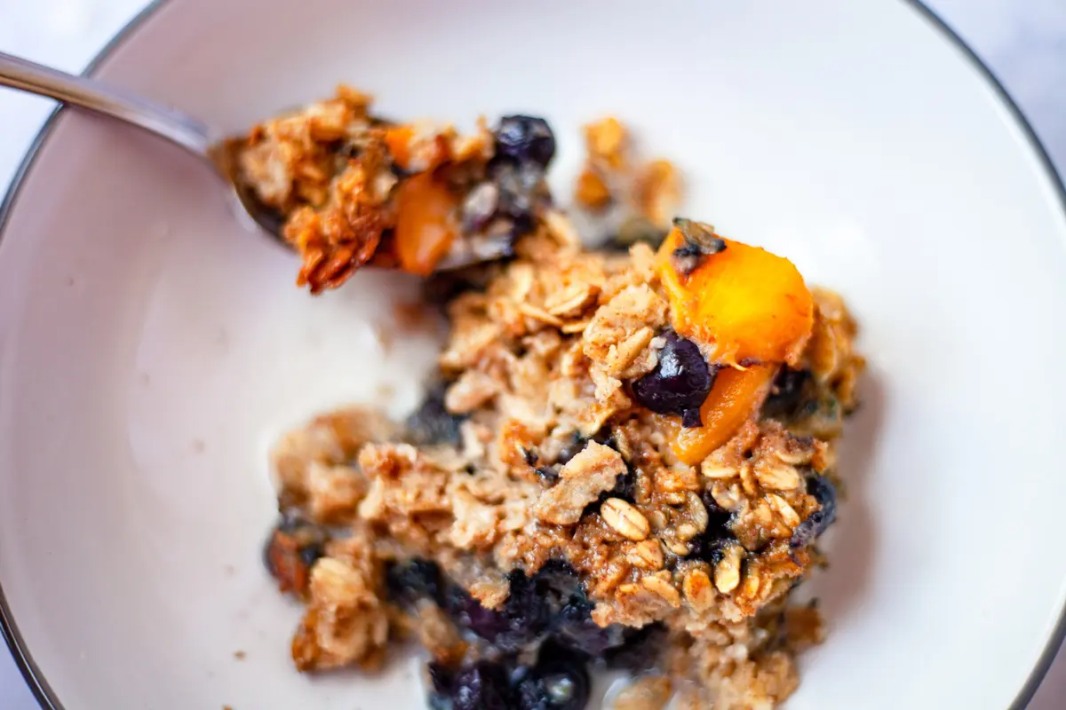 peach berry baked oatmeal in a bowl with almond milk