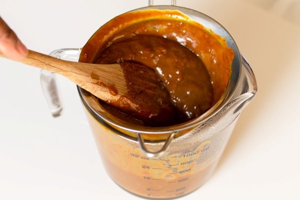 carolina style barbecue sauce being strained through a sieve