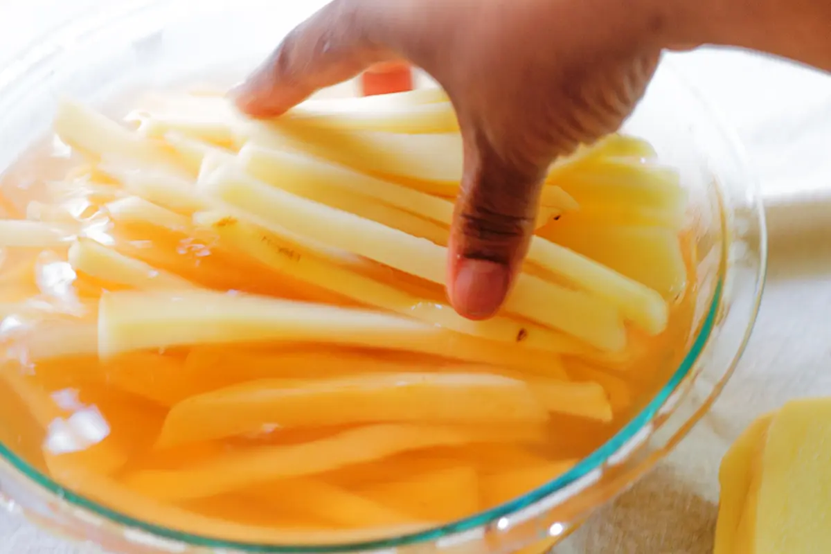 cut fries submerged in a bowl of cold water