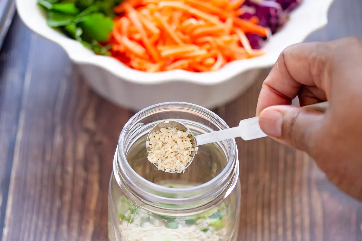 adding sesame seeds to the dressing