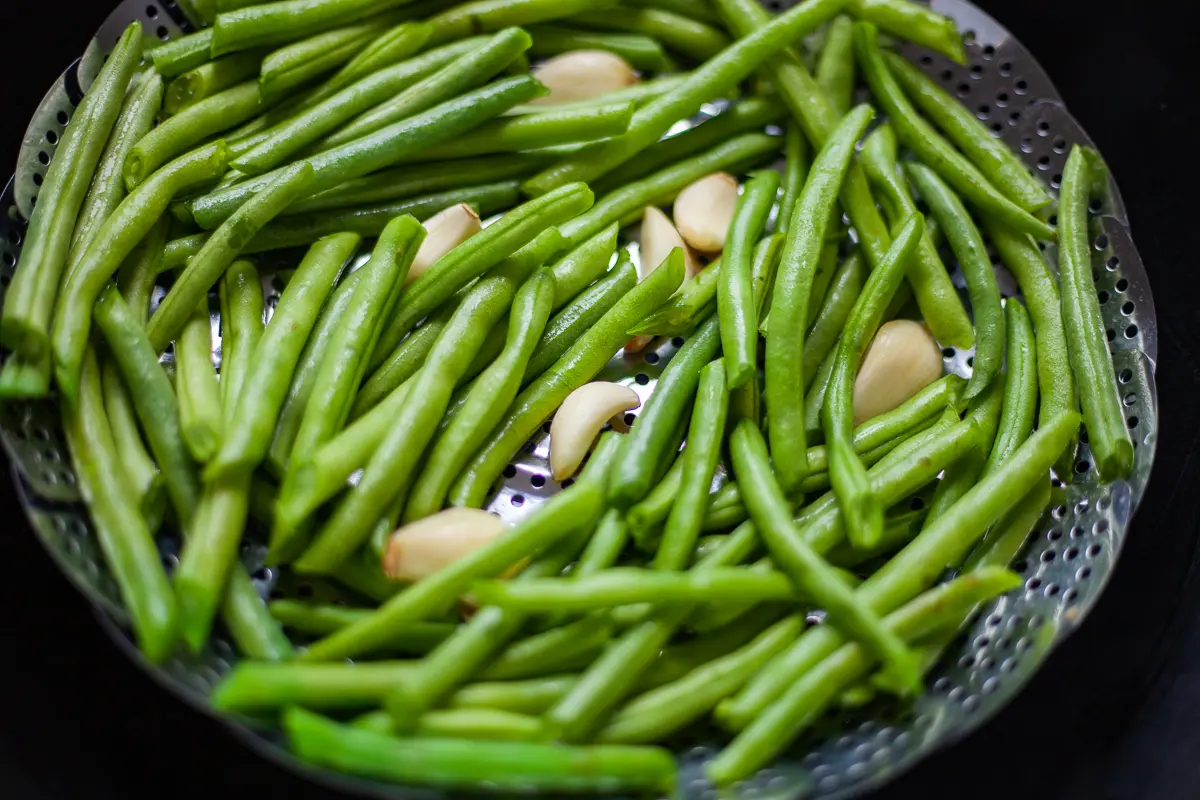 green beans and garlic in a steaming basket