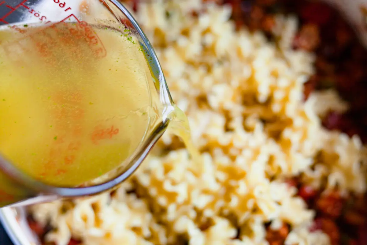 pouring chicken stock into a pot